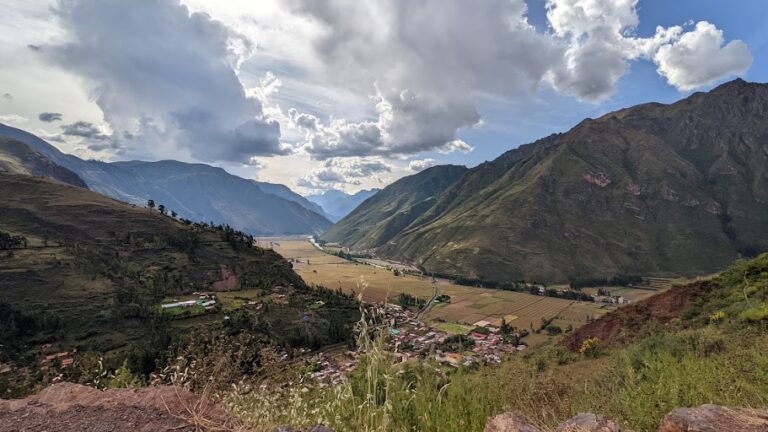 a view of a river valley surrounded by mountains and a dramatic cloudy sky