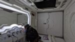 A sleeping pod with mirror on the side and door at the far end