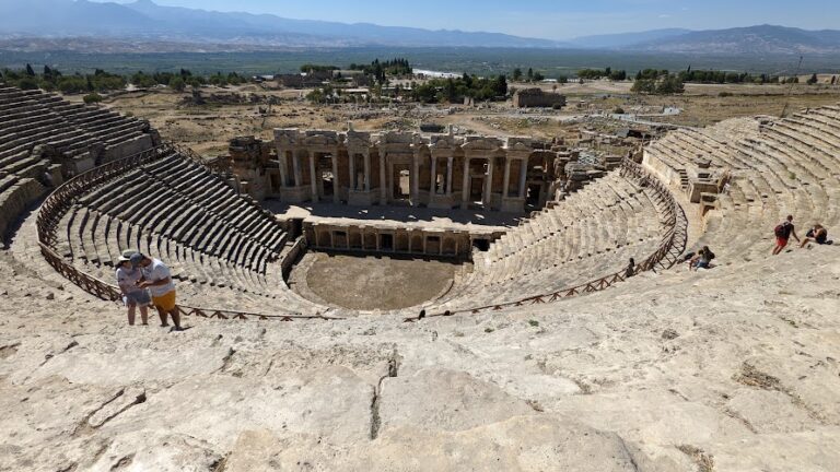 A restored Roman amphitheatre, viewed from the top of the seating area, looking down at the stage
