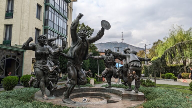 An outdoor sculpture of a group of joyful people dancing in a circle