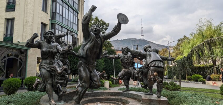An outdoor sculpture of a group of joyful people dancing in a circle